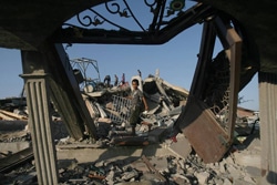 空爆で破壊された家の瓦礫の中を歩くパレスチナの男の子。