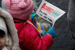 デモ参加者数人が死亡したと報じる新聞を読む子ども