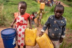 タンガニーカ州にある国内避難民の居住地の近くで、水を汲みに行く子どもたち。(2020年10月撮影)