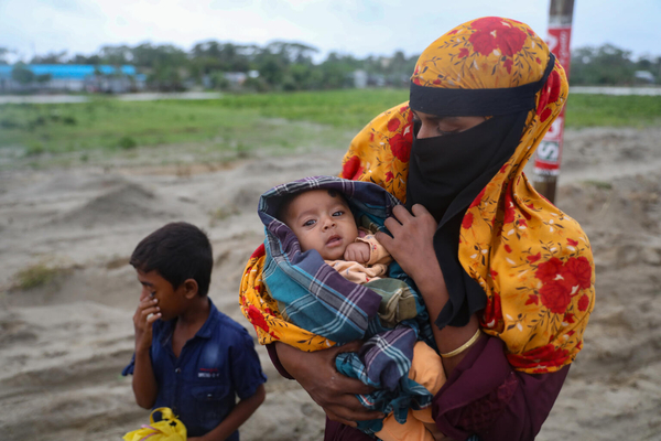 サイクロンが上陸する前に、最低限の荷物を持ち、雨の中、避難所へ向かう親子。(バングラデシュ、2024年5月26日撮影)