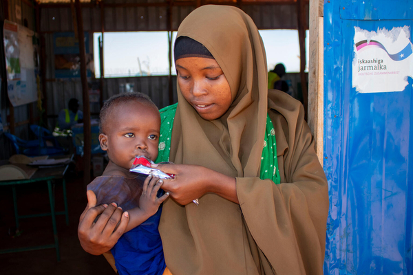 干ばつや洪水の被害を受け、国内避難民キャンプへ逃れた母親と生後7カ月のファヒアちゃん。重度の急性栄養不良のため、すぐに食べられる栄養治療食(RUTF)による治療を受けている。(ソマリア、2024年1月撮影)