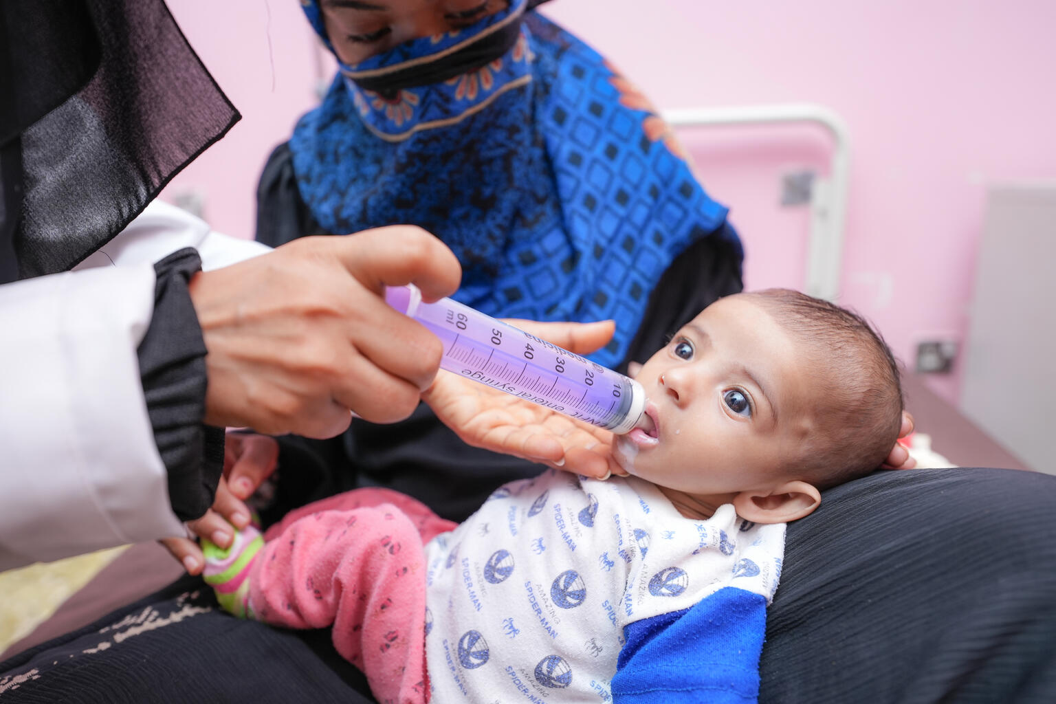 母親のラニームに抱かれながら、治療用ミルクを飲むサナドちゃん（イエメン、2023年3月7日撮影）