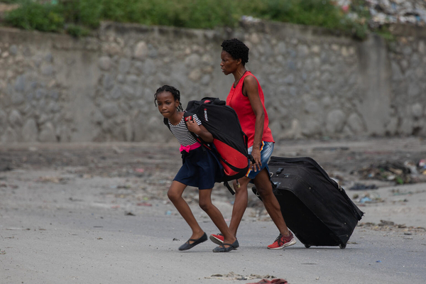 首都ポルトープランス中心部のSolino地区で起きた武装集団の襲撃後、家を捨てて逃げる親子。(ハイチ、2024年5月1日撮影)