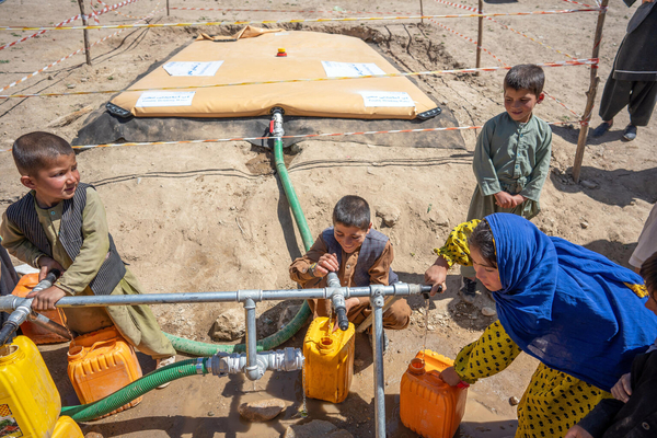 西部ゴール州で、ユニセフの支援により届いた安全な水を汲む子どもたち。ユニセフは5000リットルの水を貯水袋に供給し、毛布や子ども服、バケツ、給水タンク、石けん、浄水剤などの衛生物資を被災した家族に届けた。(アフガニスタン、2024年5月28日撮影)