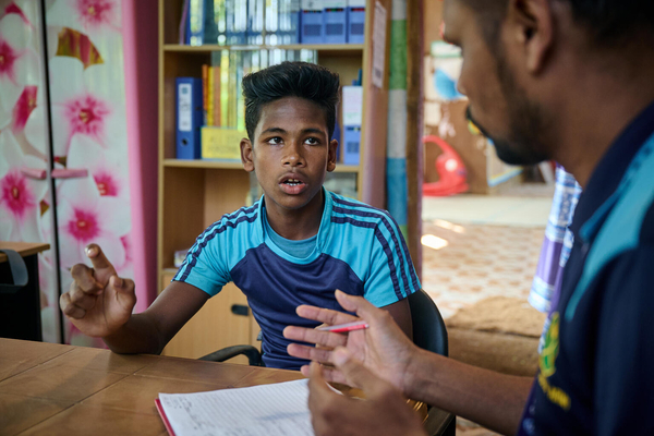 コックスバザールのロヒンギャ難民キャンプにある支援センターで、ケースワーカーと話す13歳のヌールさん。ヌールさんは家族から身体的虐待を受け、通っていた学習センターから連れ出されて働くことを強いられた。(バングラデシュ、2023年11月撮影)