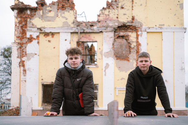 ハルキウの破壊された学校の前に立つステパンさん(右・15歳)とヤロスラフさん(左・16歳)。オンライン授業を受けているが、電力不足でネットが使えないこともある。(ウクライナ、2023年12月撮影) 