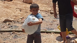 避難所の給水場所で長い間並んで汲んだ水を持ち帰る男の子