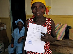 エボラ治療センターから退院し、エボラから回復したという証明書を見せる女性。（シエラレオネ）