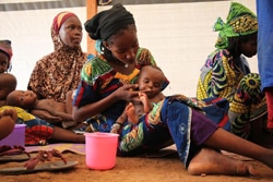 栄養不良に陥った子どもにすぐ口にできる栄養治療食を与える母親。