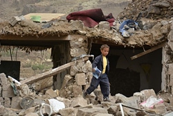 空襲で被害にあった家の瓦礫の中を歩く男の子。